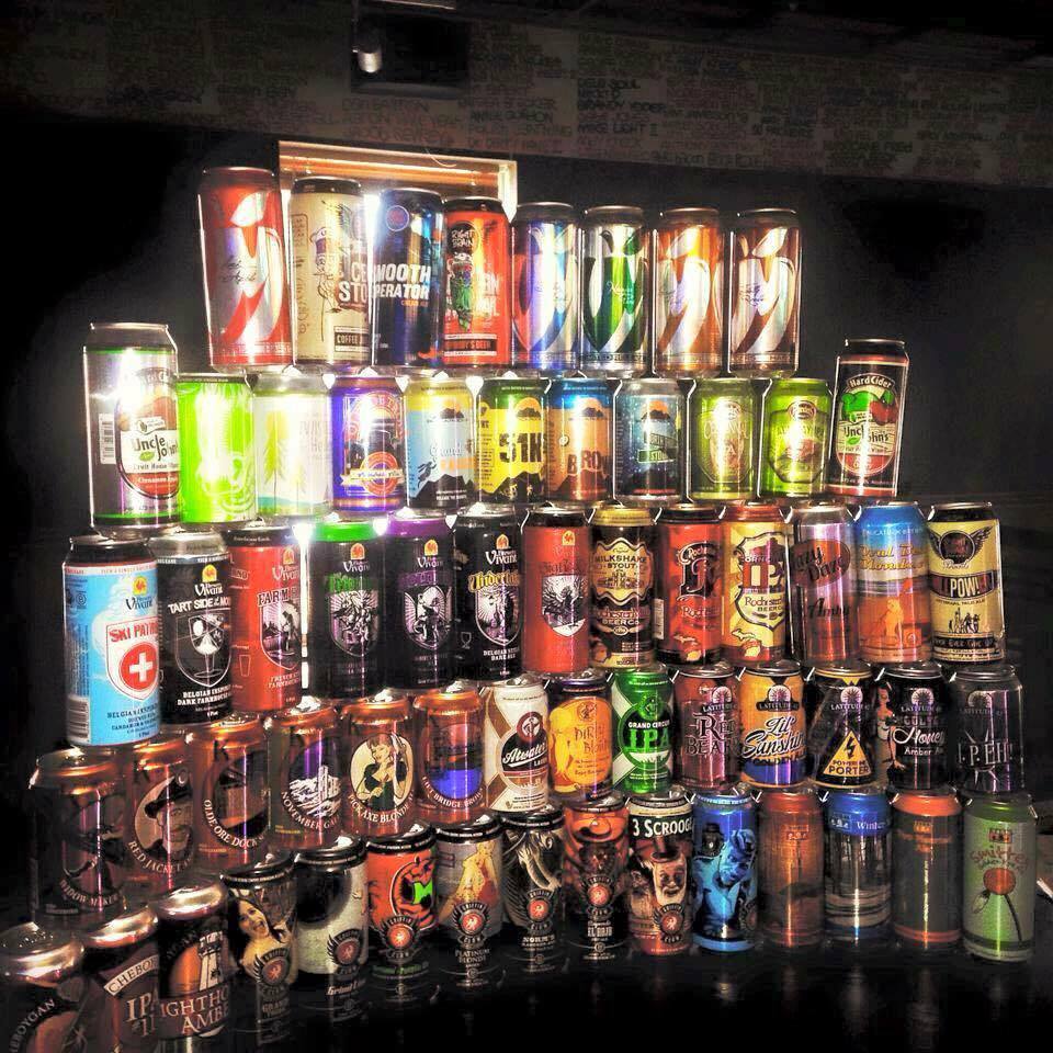 The Tin Can Bar's signature wall of canned beer — a towering pyramid of 80+ craft cans.